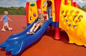 close-up of rubber tiles playground safety surface with slide in background